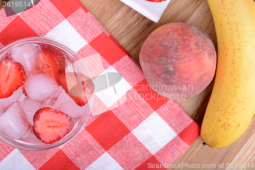 Image of A slice of red strawberry on glass plate with bananas and peach, health food concept