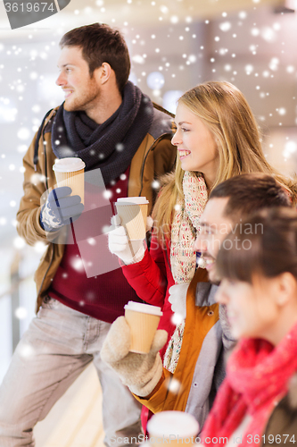 Image of happy friends with coffee cups on skating rink