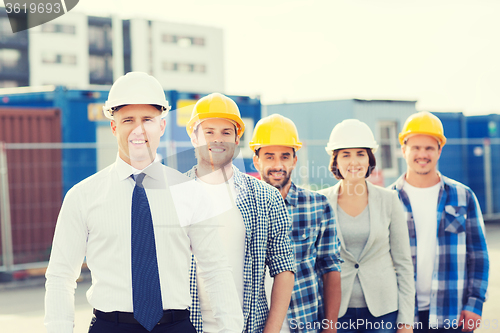 Image of group of smiling builders in hardhats outdoors