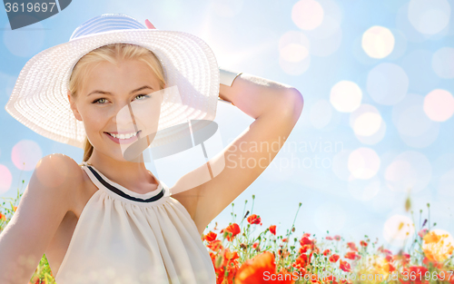 Image of smiling young woman in straw hat on poppy field