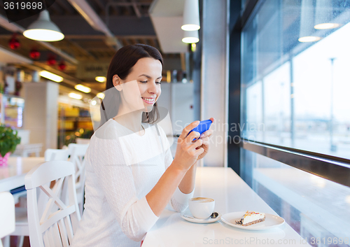 Image of smiling woman with smartphone and coffee at cafe