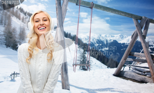 Image of smiling young woman in winter earmuffs and sweater