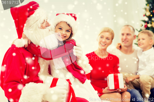 Image of smiling family with santa claus and gifts at home