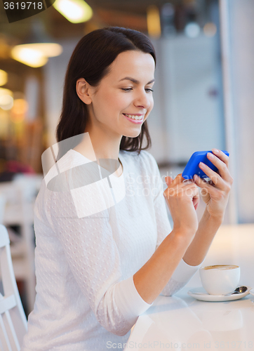 Image of smiling woman with smartphone and coffee at cafe