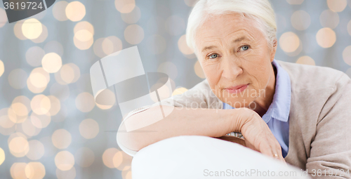 Image of happy senior woman resting on sofa over lights