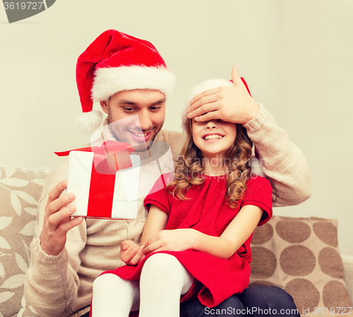 Image of smiling father surprises daughter with gift box