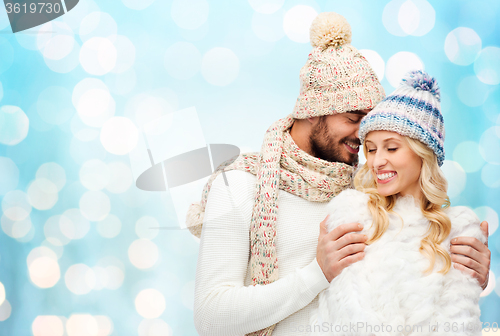 Image of happy couple in winter clothes hugging over lights