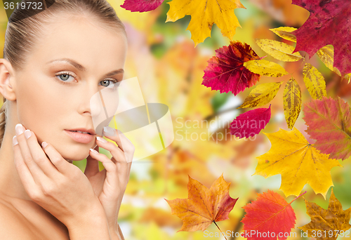 Image of beautiful woman touching her face over autumn