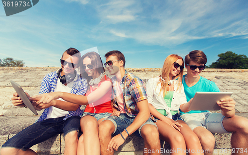 Image of group of smiling friends with tablet pc outdoors