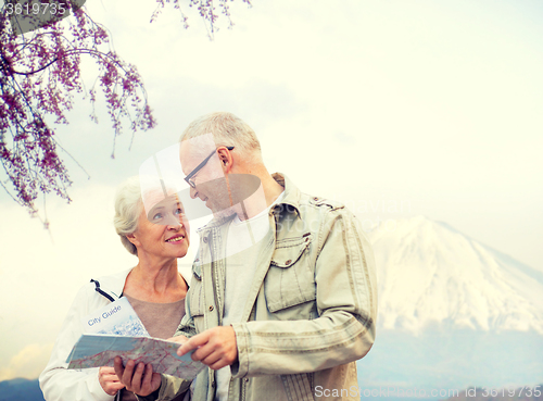Image of happy senior couple with travel map over mountains