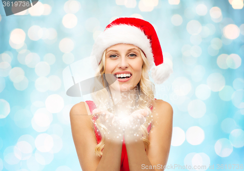 Image of happy woman in santa hat with fairy dust on palms