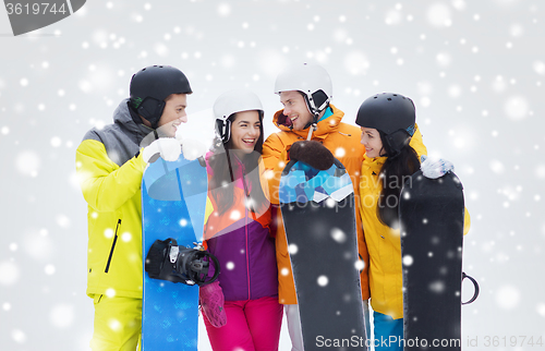 Image of happy friends in helmets with snowboards talking