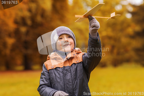 Image of happy little boy playing with toy plane outdoors