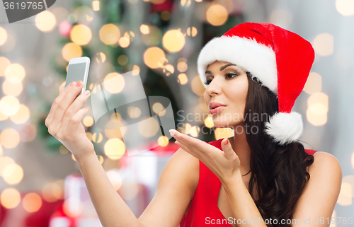 Image of woman in santa hat taking selfie by smartphone