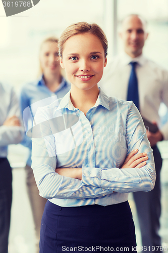 Image of smiling businesswoman with colleagues in office