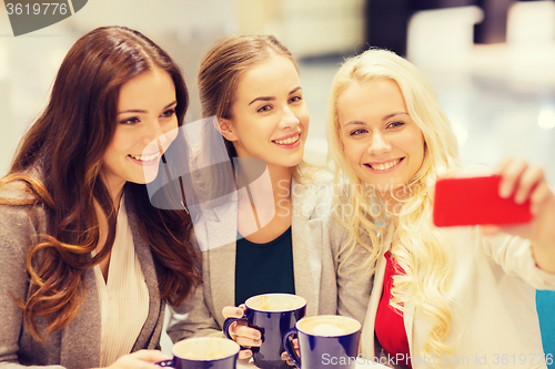 Image of smiling young women with cups and smartphone