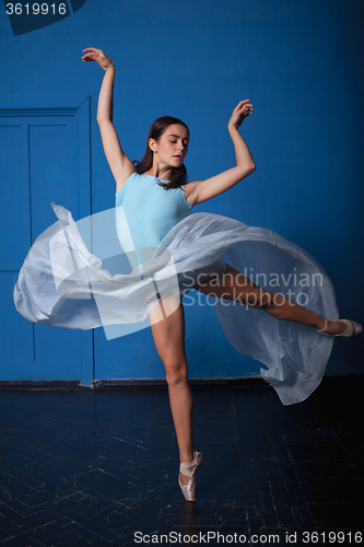 Image of young modern ballet dancer posing on blue background