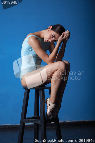Image of young modern ballet dancer posing on blue background