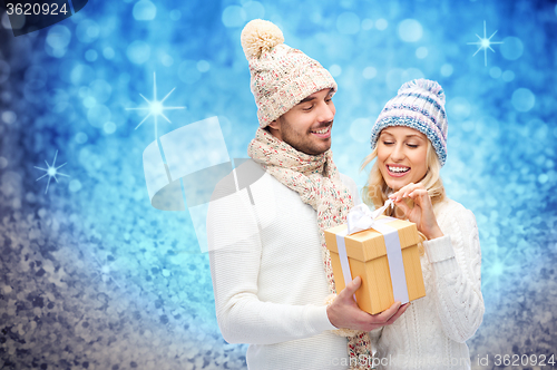 Image of smiling couple in winter clothes with gift box