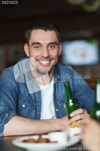 Image of happy young man drinking beer at bar or pub