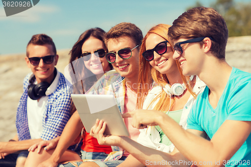 Image of group of smiling friends with tablet pc outdoors