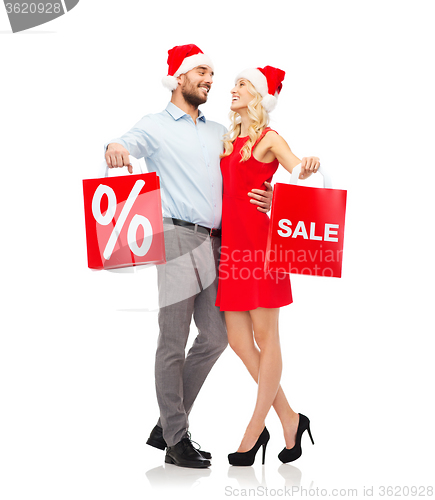 Image of happy couple in santa hats with red shopping bags