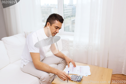 Image of man with papers and calculator at home