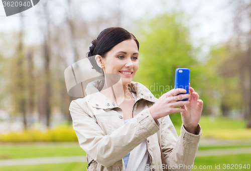 Image of smiling woman taking picture with smartphone