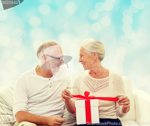 Image of happy senior couple with gift box at home