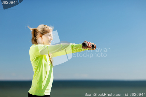 Image of sporty woman with light dumbbells outdoors