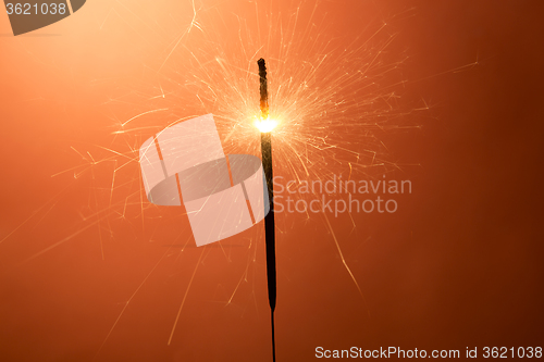 Image of Burning sparkler on an orange background