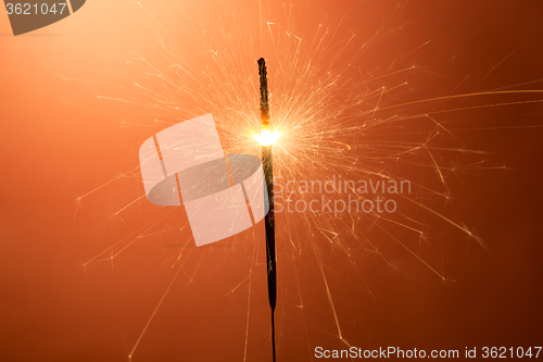 Image of Burning sparkler on an orange background