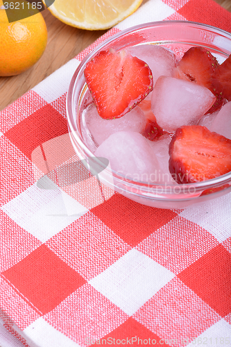 Image of A slice of red strawberry on glass plate with lemon and mandarin in party theme background