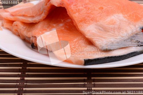 Image of Raw salmon fish steaks with fresh herbs on white plate