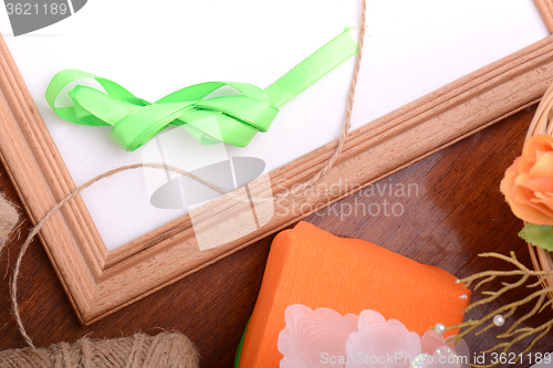 Image of Christmas gift box and empty wooden frame on wooden table