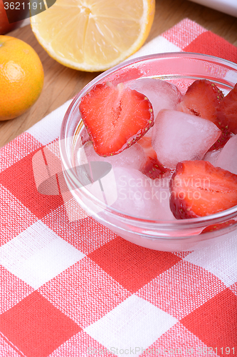 Image of A slice of red strawberry on glass plate with lemon and mandarin in party theme background