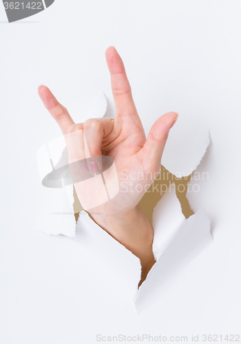 Image of Peace sign gesture break through the paper wall