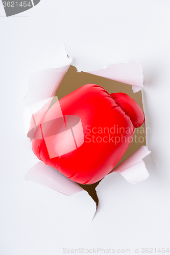 Image of Hand in boxing glove through paper hole