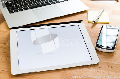 Image of Working table with cellphone and digital tablet showing a blank 