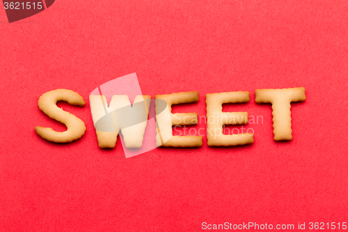 Image of Word sweet biscuit over the red background