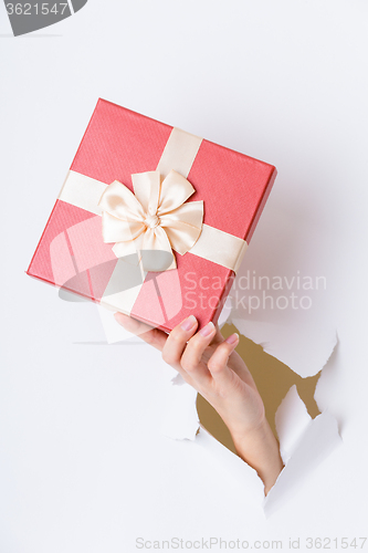 Image of Hand break through paper with red gift box
