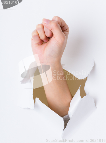 Image of Arm fist breaking through the paper wall