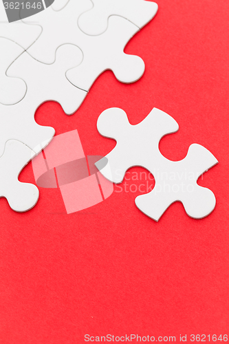 Image of Incomplete white puzzle with red color background