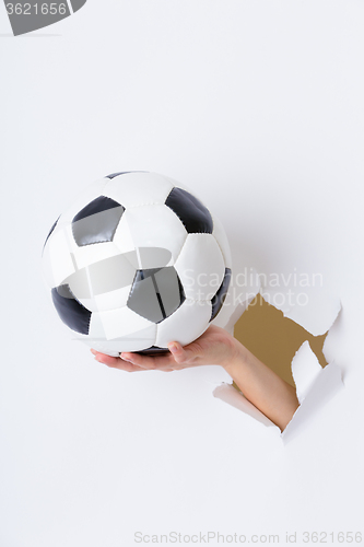 Image of Hand break through paper with soccer ball