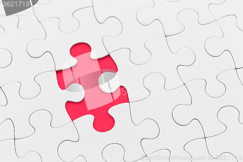 Image of Jigsaw puzzle with missing piece over red background