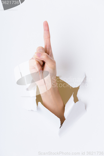 Image of Woman hand breaking through paper wall with finger point up