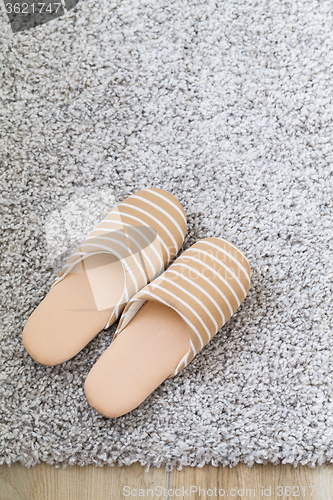 Image of Brown slippers on grey carpet