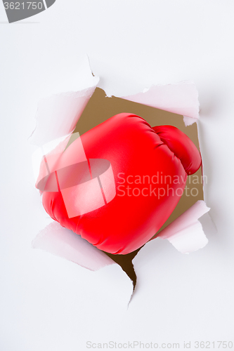 Image of Punching boxing glove though over white paper