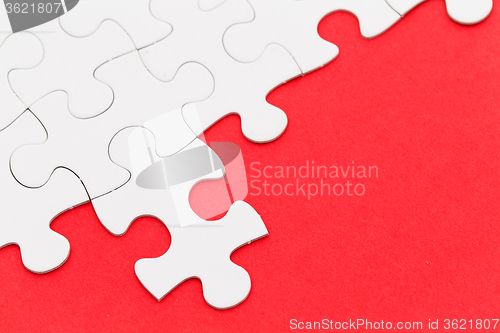 Image of Incomplete white puzzle with red color background