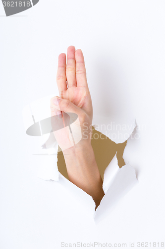 Image of Woman breaking through a paper wall showing three finger